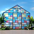Colorful Stained Glass House Surrounded by Lush Plants Under Clear Blue Sky