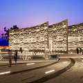 Park Landscape At Evening With Illuminated Stone Wall Fountains Curved Walkway And People Strolling