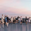 Group of People Relaxing Outdoor Evening Sitting on Benches with Sunset Sky and Smartphones
