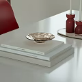 Decorative Ornament Set with Metallic Bowl Red Candle Holders and Book Stack on White Table