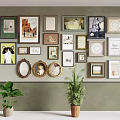 Wall Decor Featuring Various Framed Artworks And Green Plants On Gray Wall