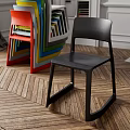 Black Leisure Chair With Colorful Stacked Chairs On Wooden Herringbone Floor Interior