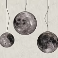 Three Textured Moon Surface Pendant Lights With Warm Glow Hanging On Gray Wall