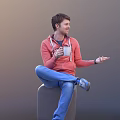 Man in Red Hoodie and Blue Jeans Holding White Cup Sitting Smiling and Gesturing