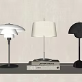 Three Modern Table Lamps With Stylish Shades Placed On Stack Of Books