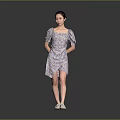 Woman In Floral Print Puffed Sleeve Dress With White Shoes Standing Against Simple Gray Background