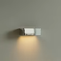 Modern Metallic Chrome Wall Lamp With Warm Light Illuminating Gray Wall
