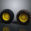 Two Black Tires Featuring Yellow Rims and Muddy Worn Tread Surfaces