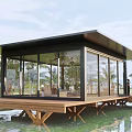 Modern Waterfront Cabin With Glass Walls And Wooden Deck Surrounded By Trees