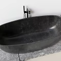 Modern Black Oval Stone Bathtub on Gray Stone Platform with Black Faucet