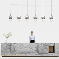 Modern Marble Reception Desk With Receptionist Standing Behind Hanging Pendant Lights And Potted Plant