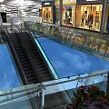 Modern Escalator In Shopping Mall Featuring Glass Railing And Surrounding Retail Shops