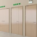 Three Wooden Doors With Green Emergency Exit Signs In Indoor Environment