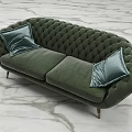 Green Tufted Two Seater Sofa With Blue Pillows Metal Legs On Marble Floor Background