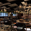 Stylish Restaurant Interior With Hanging Chandeliers Dining Tables Wine Racks And Green Plants