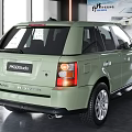 Light Green Range Rover SUV Rear View In Modern Indoor Showroom With Billboard