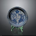 Blue and White Decorative Plate With Floral Border And Two Figure Designs On Green Stand