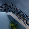 Ornate Staircase With Black Iron Railings Blue Wall Green Plant Black Vases And Pebble Decor