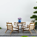 Landscape Seating with Wooden Chairs Round Glass Table Blue Vase Purple Flowers and Green Plants