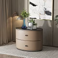 Beige Two Drawer Bedside Table With Circular Top Blue Vase Green Plants Photo Frame Potted Plant