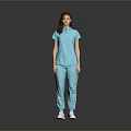 A woman in light blue top and pants standing against gray background wearing white shoes