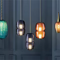 Stylish Glass Pendant Lights with Various Colors Blue Orange Gold Hanging Against Dark Wall