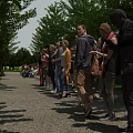 People Standing in Line on Outdoor Park Path With Trees and Grass