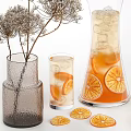 Refreshing Orange Beverage in Glass Pitcher and Cups with Ice Cubes Slices and Dried Flowers