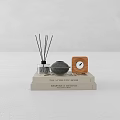 Stack of Detailed Interiors Books with Reed Diffuser Gray Sphere and Wooden Clock