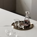 Transparent Wine Bottle With Dark Liquid And Glasses On Metal Tray White Marble Tabletop