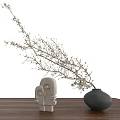 Black Ceramic Vase with Branches and Small White Flowers on Wooden Table with White Figurines