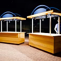 Outdoor Wooden Stalls With Blue Canopies Red Brick Floor And Person Standing At Counter
