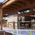 Wooden Guesthouse Building With Sloped Roof Large Windows And Outdoor Terrace Surrounded By Lush Plants