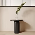 Black Round Top Side Table With Cylindrical Base Green Leaf Vase Against Light Wall 3d model