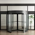 Modern Revolving Glass Door Entrance With Black Frame And Indoor Plant