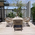 Outdoor Patio Rattan Dining Table And Chairs With Striped Cushions Surrounded By Green Plants