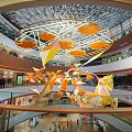 Modern Shopping Mall Interior With Large Orange Geometric Hanging Decorations And Glass Curtain Walls