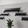 Multiple Black Roof Tile Shaped Wall Decor Arranged On Gray Wall With Green Plant