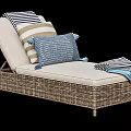 Wicker Lounge Chair with Beige Cushion Striped Pillows and Blue Throw Blanket