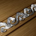 Elegant Metal Carved Decorative Strip With Scroll Patterns On Wooden Surface