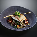 Pan-Seared Cod Fillet with Fresh Herbs Cherry Tomatoes and Greens in Dark Bowl