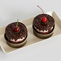 Two Moist Chocolate Cupcakes with Fresh Cherry Topping on Beige Tray