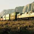 Freight Train Carrying Containers Moving Through Mountainous Landscape With Dry Grass 3d model