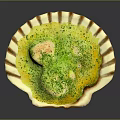 Creamy Yellow Savory Dish Served in Shell Shaped Plate Topped with Green Seasoning and White Chunks