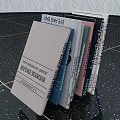 Stacked Books And Magazines With Diverse Cover Designs On Speckled Desktop Surface
