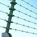Industrial Security Barbed Wire Fence With Green Insulators Yellow Warning Signs And Concrete Base