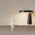 Modern Table Lamp With Black Shade Dark Base Warm Lighting And White Figurine On Shelf