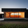 Modern Detached House Featuring Black Exterior Large Glass Windows Sunset Glow and Illuminated Interior