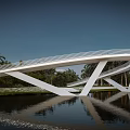 Curved Scenic Bridge With Wooden Deck And White Structure Over Water Surrounded By Palm Trees
