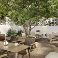 Outdoor Restaurant Courtyard With Green Trees White Building Canopy And Garden Seating